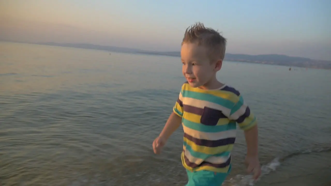 Happy boy running on the sea coast at sunset