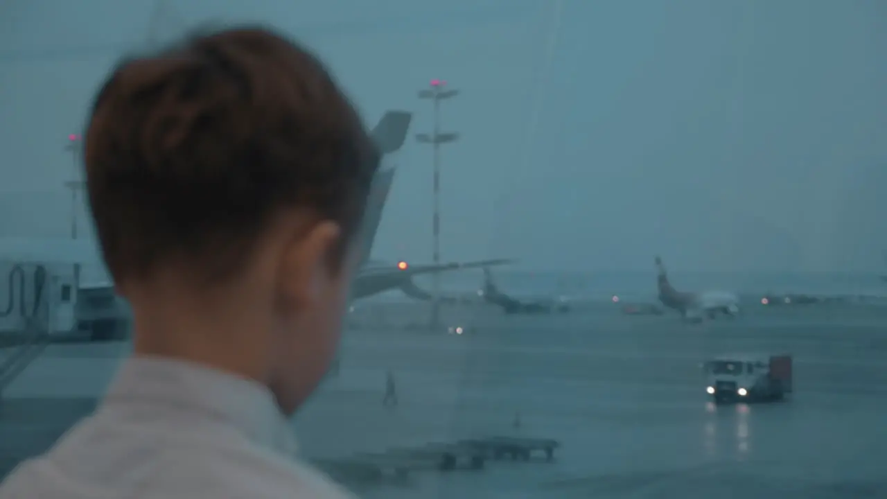 Boy waiting for flight at the airport and watching planes