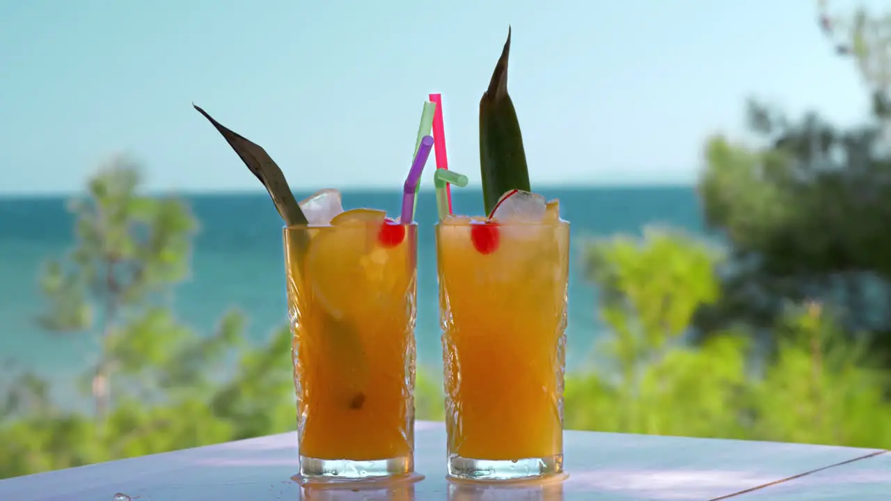 Refreshing fruit drinks with ice cubes falling into glasses