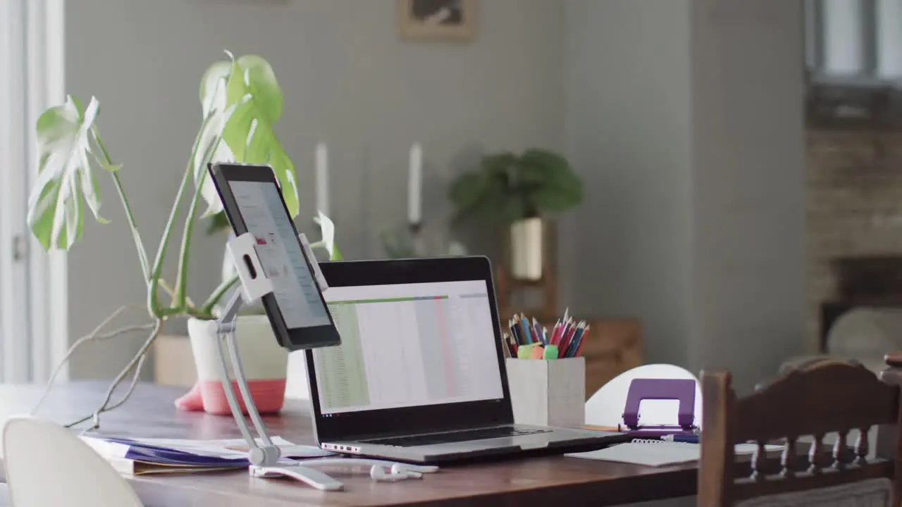 Empty house room with laptop and tablet with graphs on screens on table in slow motion