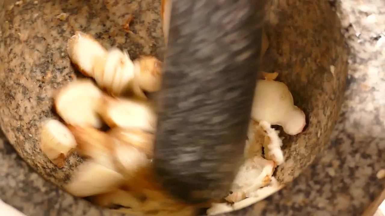 Crushing Fresh Galangal in Stone Mortar Close Up