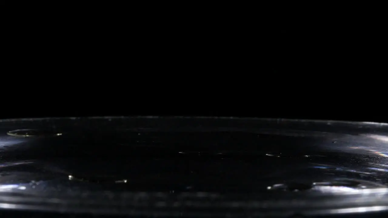 Droplets of Oil Splash in Slow Motion into Water Isolated on Black Background