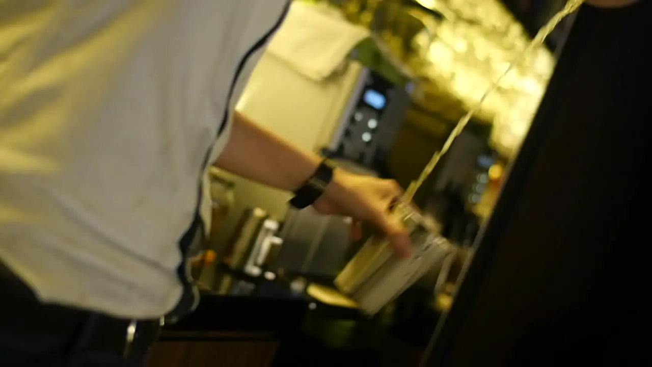 Cocktail being mixed between two stainless steel cups by professional bartender in slow motion close up shot