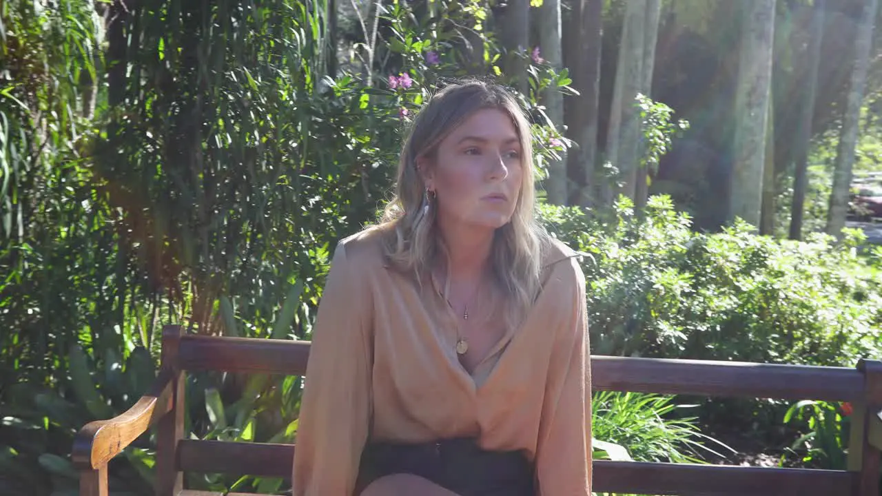 Young female sitting on park bench in garden looking around_slow motion