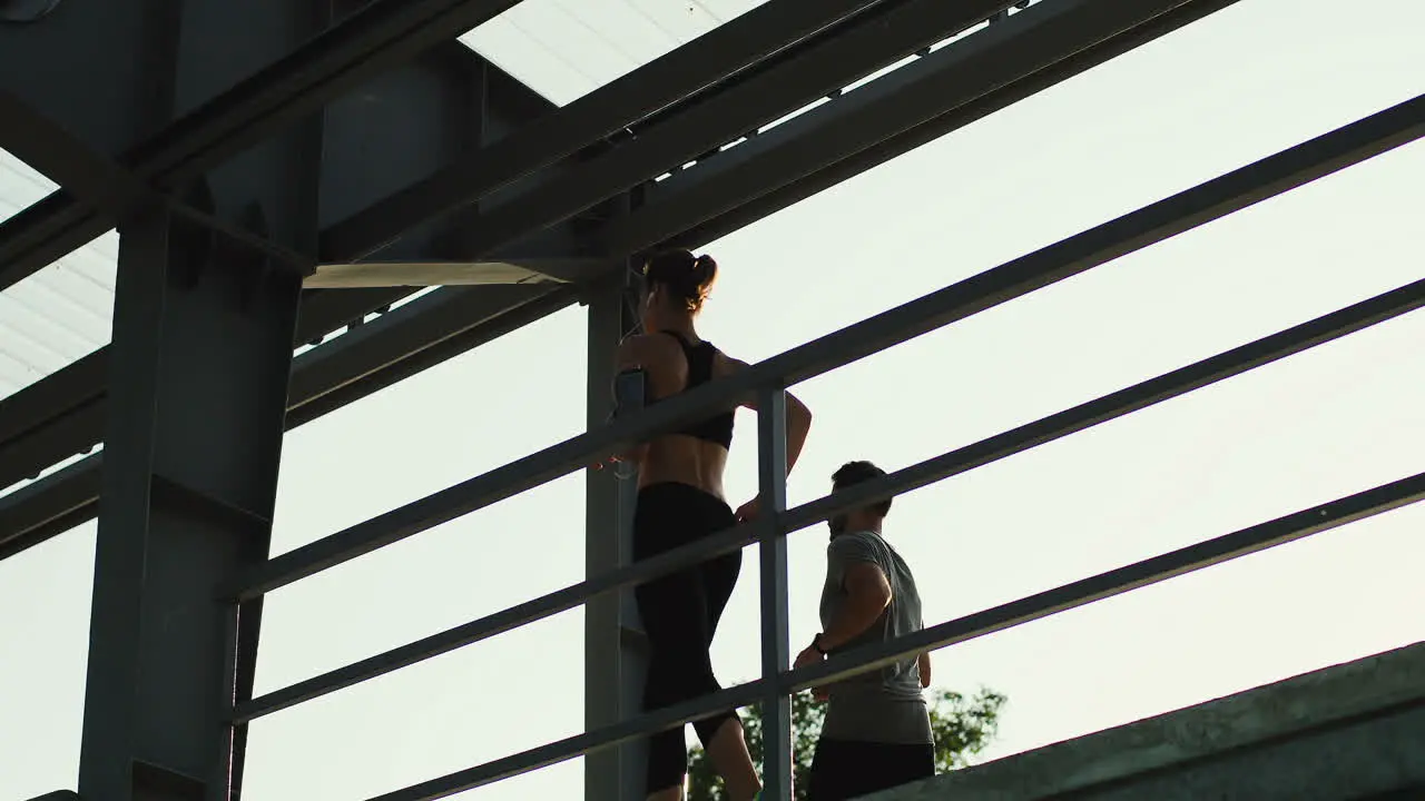 Young Couple Of Joggers Running At The Stadium Passage While Doing Sport In The Morning