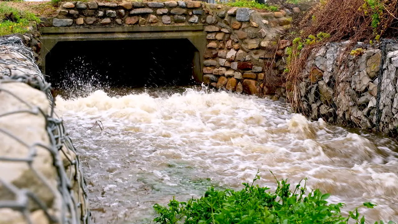 Rainwater gushing out of storm drain on coastline static real time