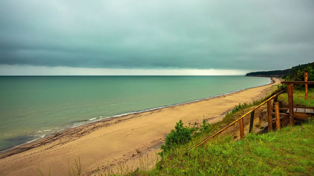 Timelapse of a beach with dark clouds over the coast waves crashing on the shore on a rainy afternoon