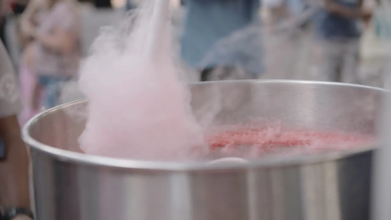 Slow motion footage of a hand spinning cotton candy around a machine