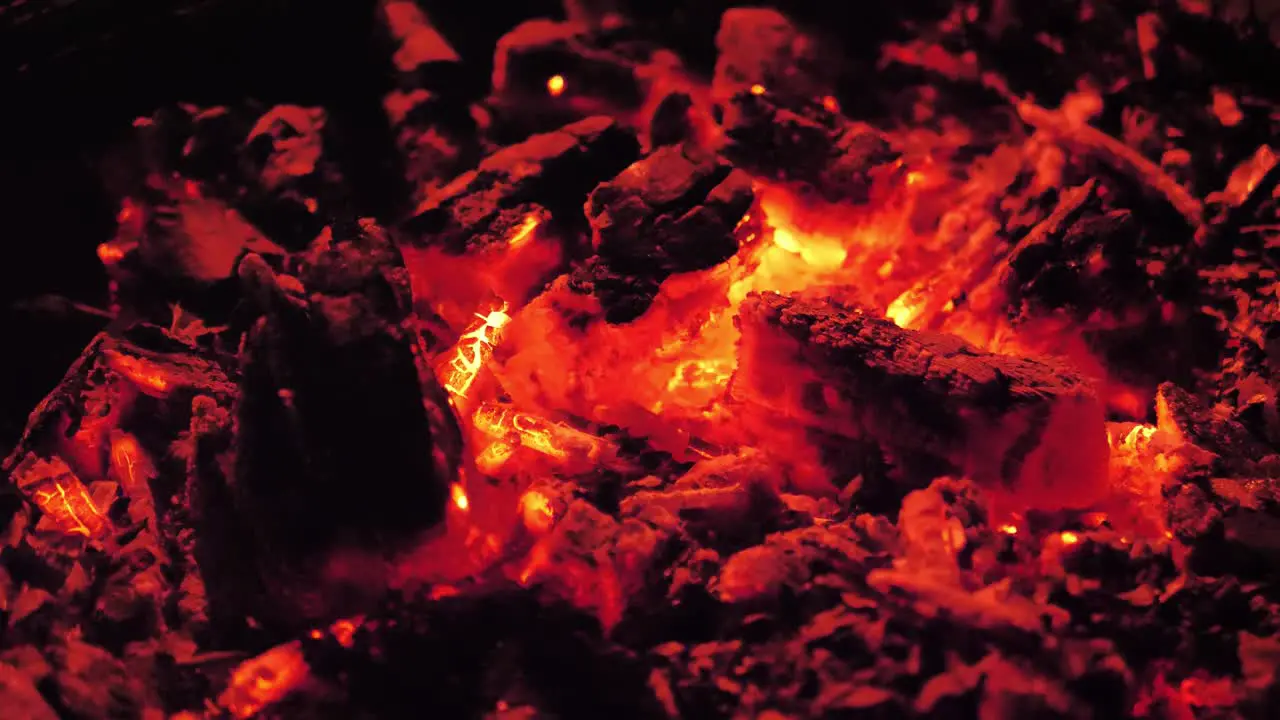 Close up slow panning shot of smoldering ashes and fire from a house fire pit in 4K 60fps