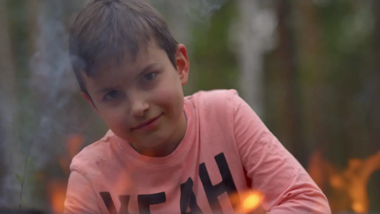 Adolescent boy looking with antipathy through line of fire flame in forest