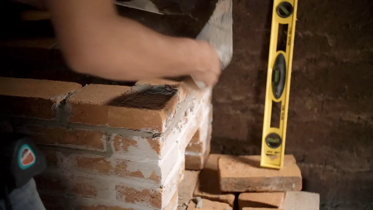 Worker in Small Mud Hut Working to Install Brick Stove