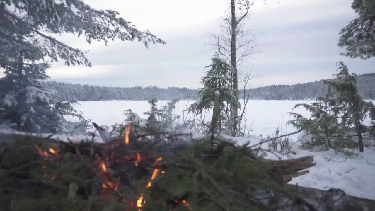 Close Up Of Campfire Burning At Daytime With Vast Wintry Landscape In Background