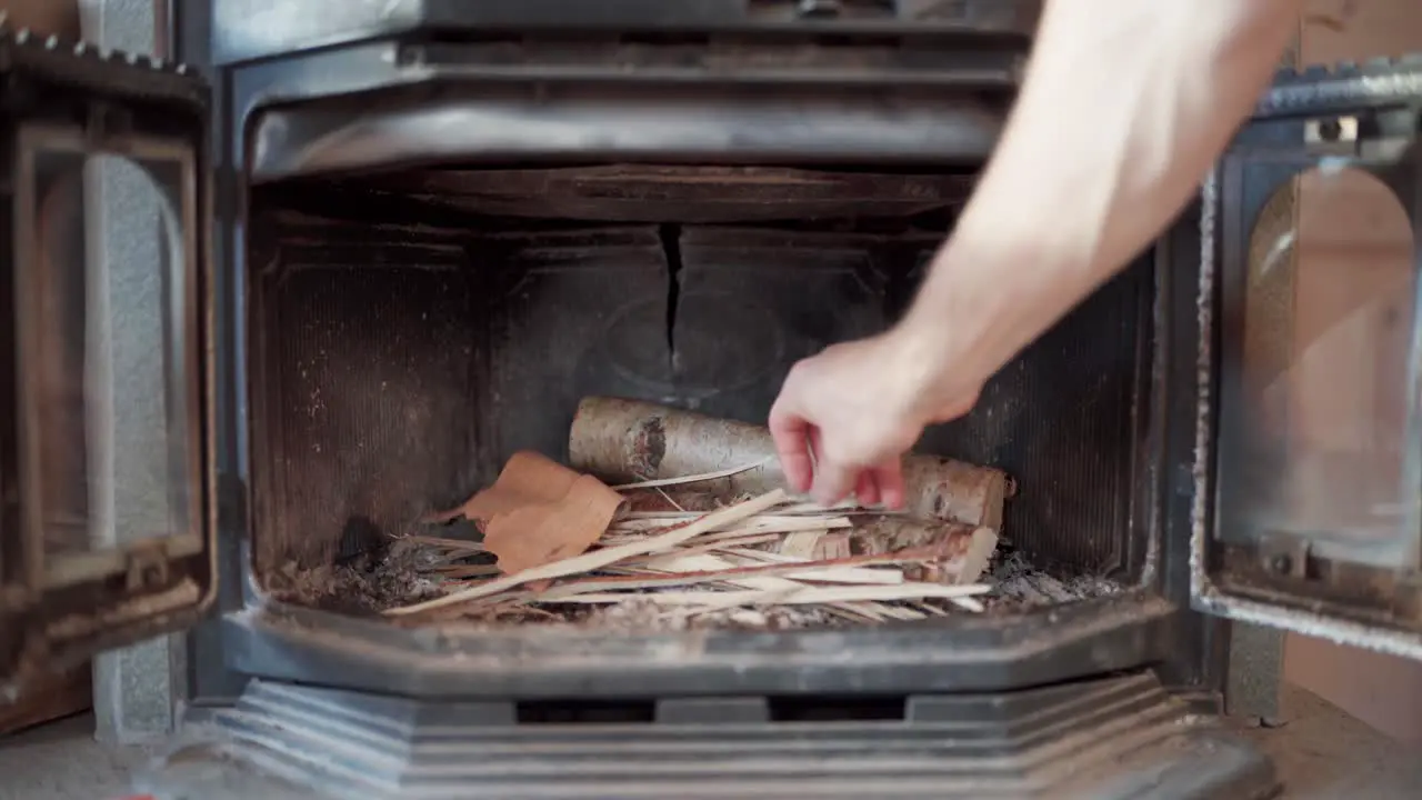 Man Placing Scraps Of Wood Inside The Traditional Heating Stove