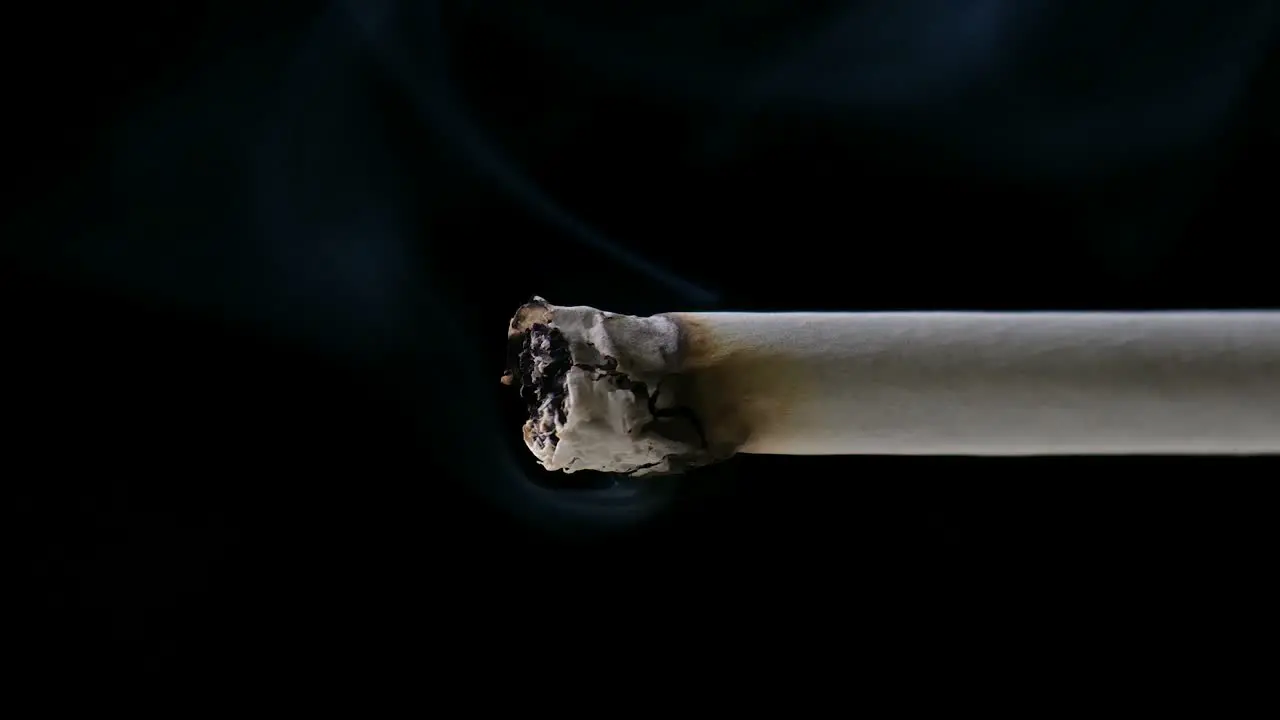 Close up clip of lit cigarette with smoke rising