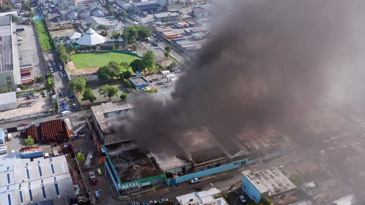 Aerial view around a factory fire a smoking city building orbit drone shot