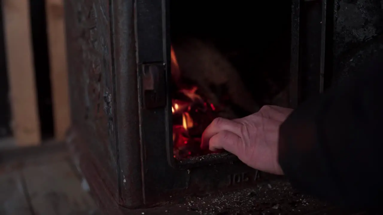 Hand Piling Up Woods Inside Furnace With Fire