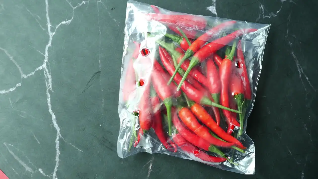 Top view of red chili in a plastic packet on black background 