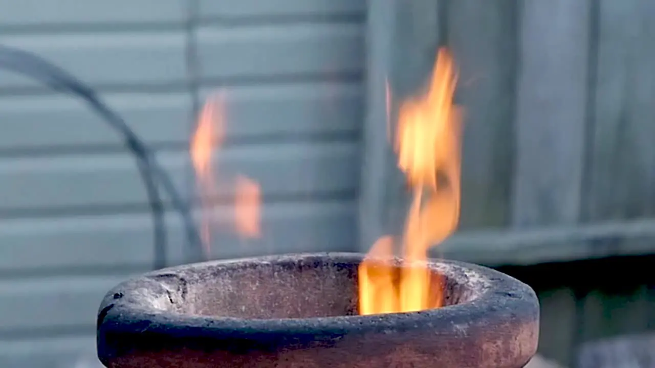 Flames lick out the top of a terra-cotta chimenea during late evening