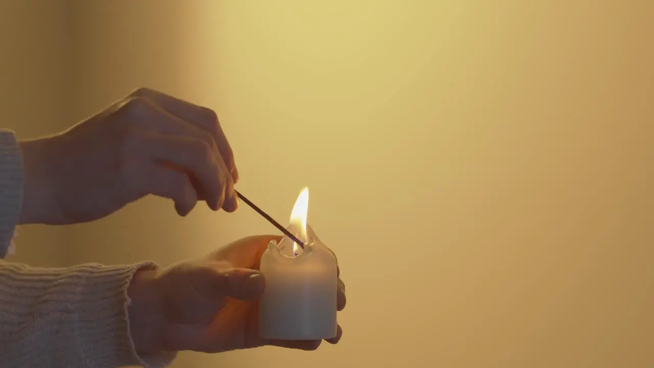 Candle being lit in front of a plain yellow background