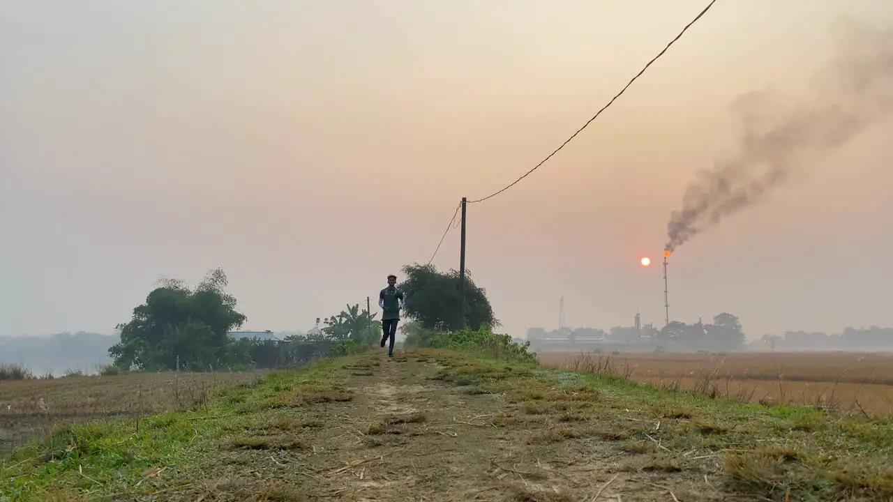 Low angle shot of man jogging towards camera in hazy morning caused by gas plant