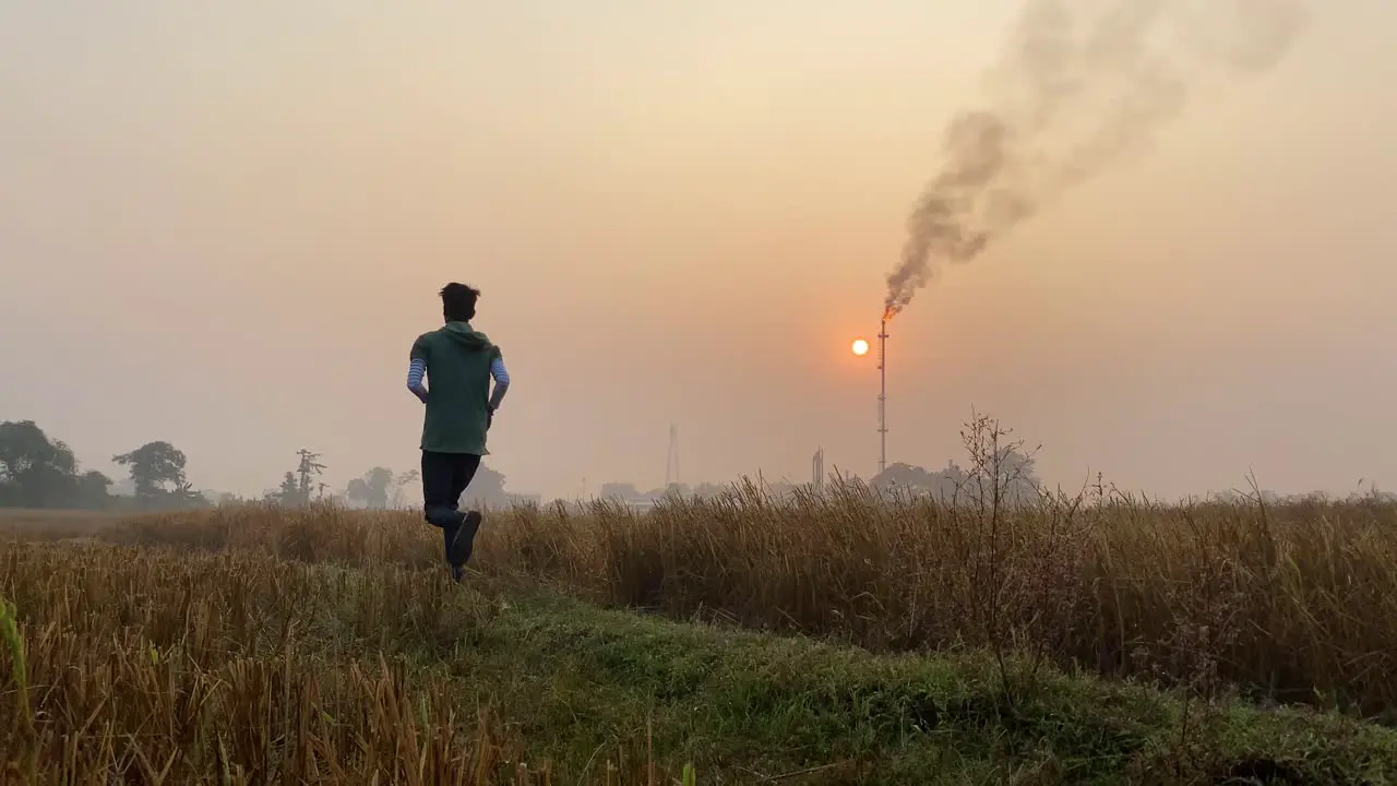 Industrial area with smokestack man jogging on rural countryside path static