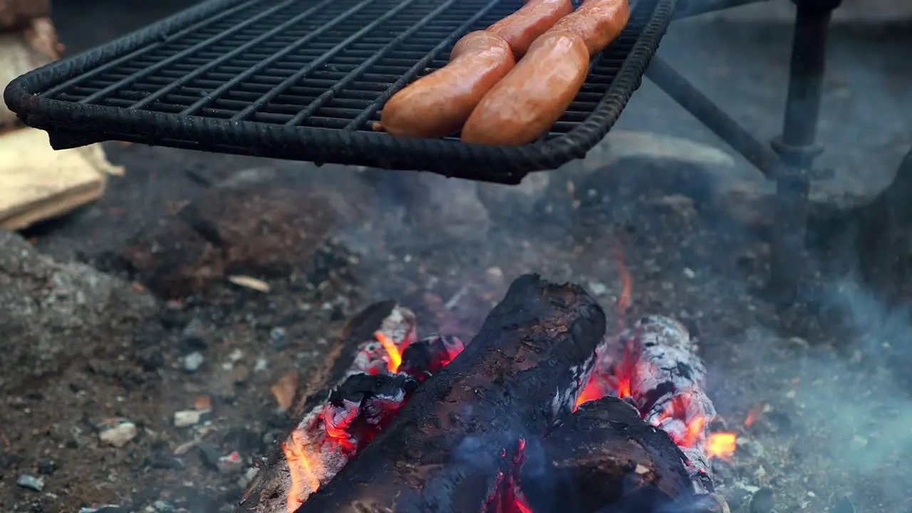 Sausages getting grilled over a soldering open fire flame grill outdoors with copy space