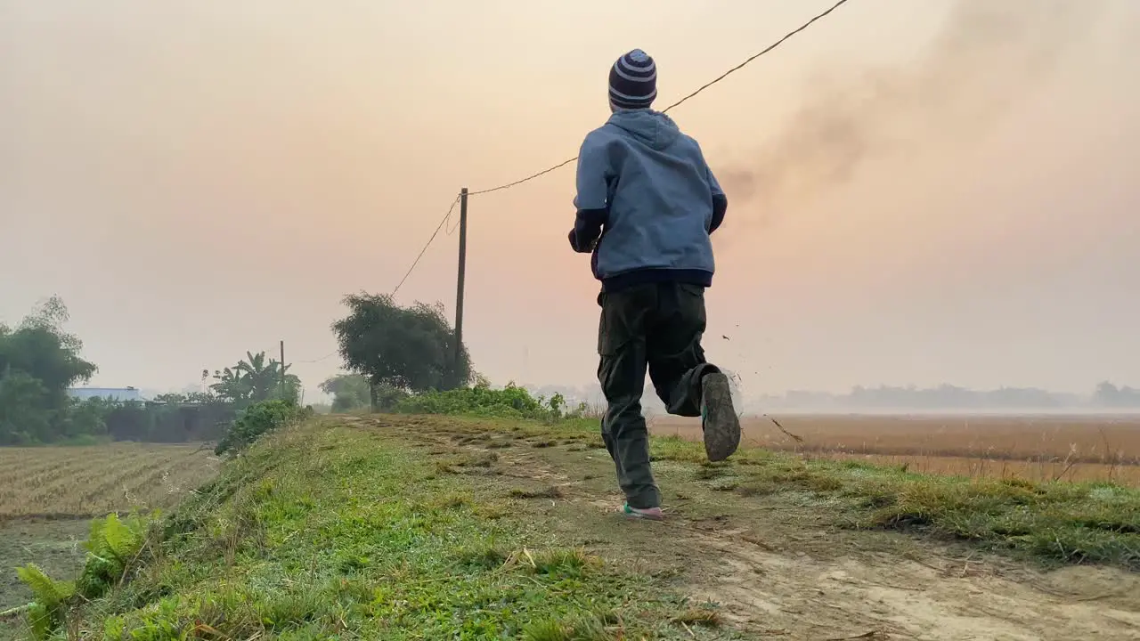 Man jogging at rural road during sunrise gas plant smoke polluting environment