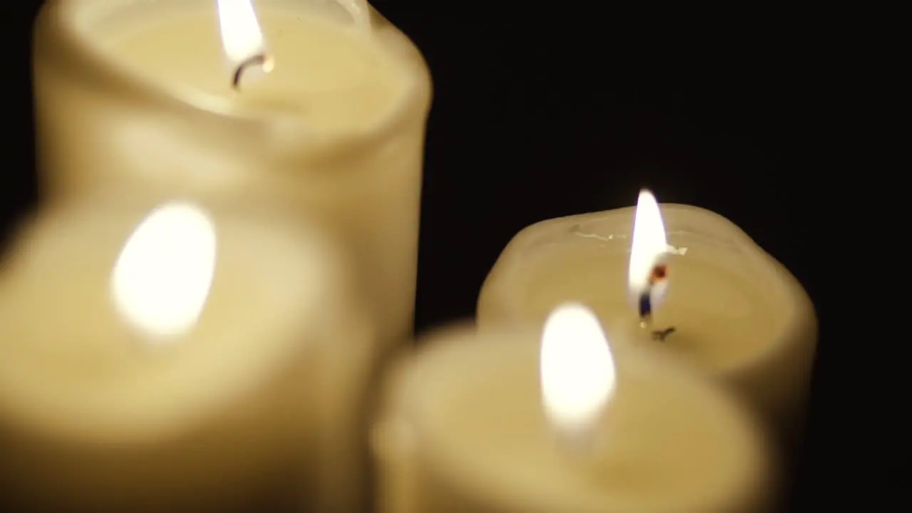 Slow movement from the mountains to the bottom of the candle four candles stand on the table gentle movement of the lit flame