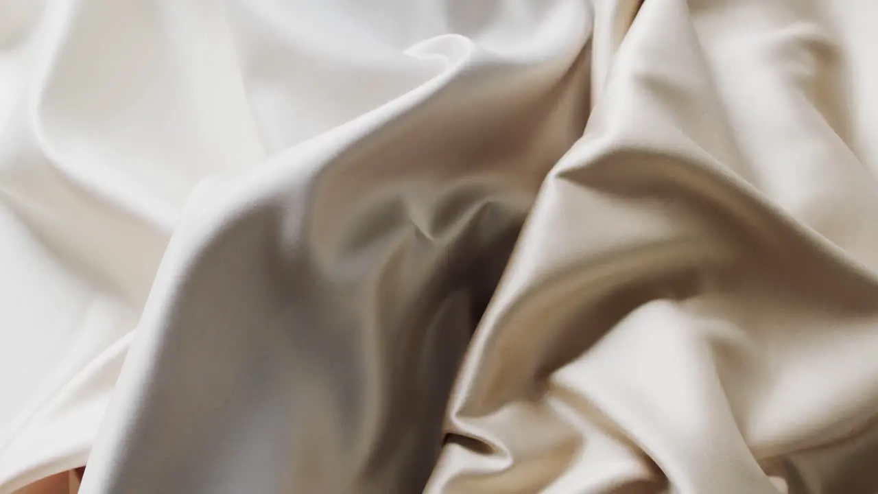 Close up of white and beige shiny silk clothes in slow motion