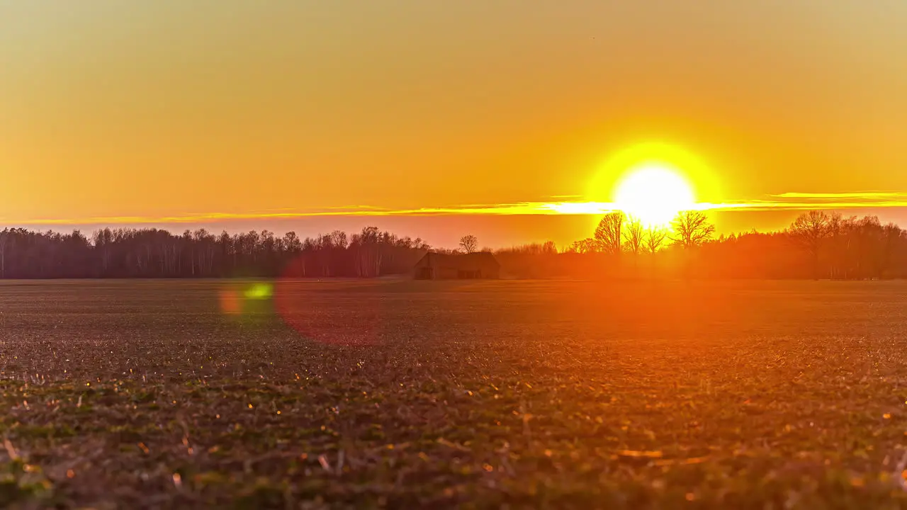 Bright sun setting down in rural landscape with silhouette of barn fusion time lapse