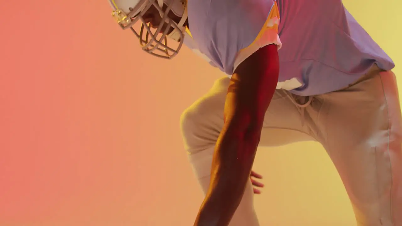 Video of midsection african american american football player with ball over orange background