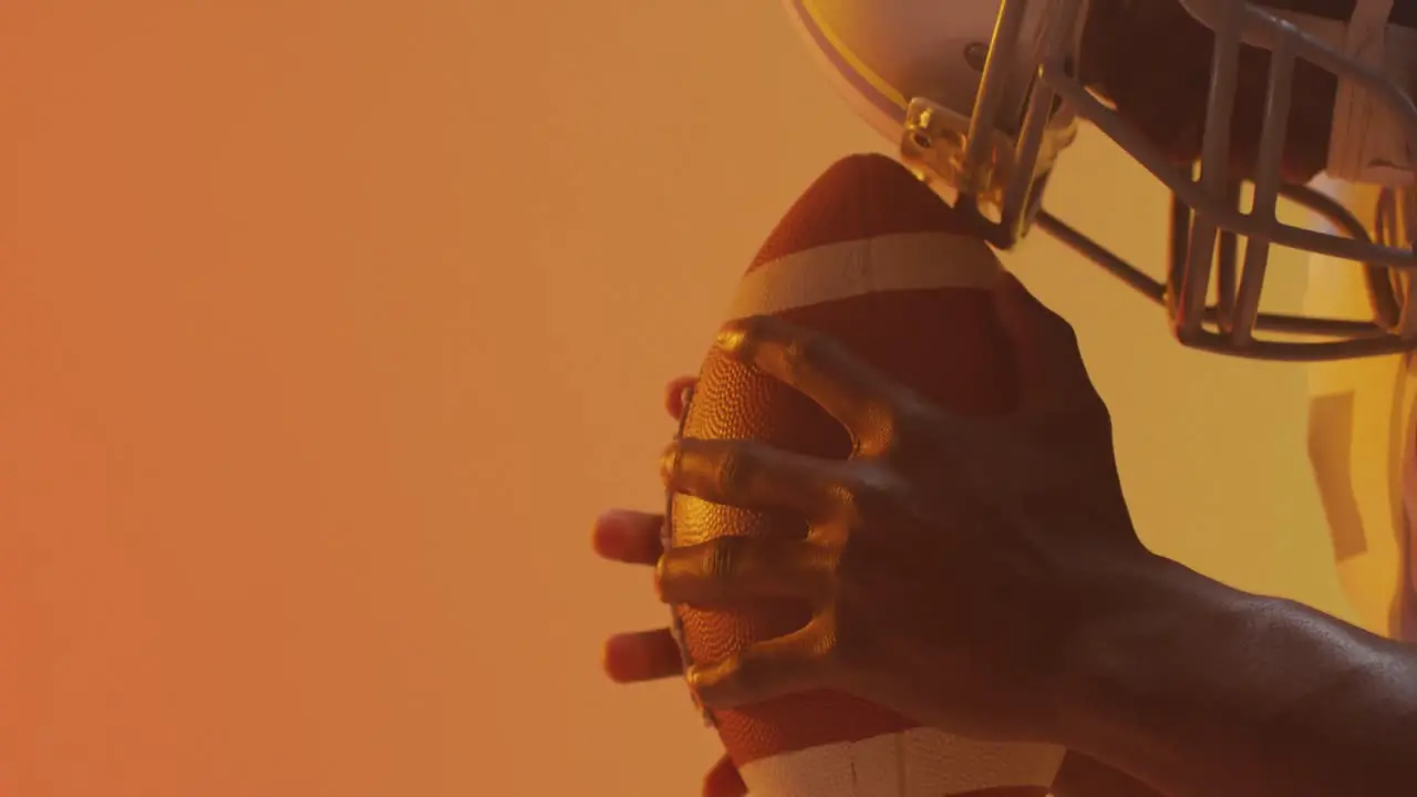 Video of african american american football player with ball over orange background