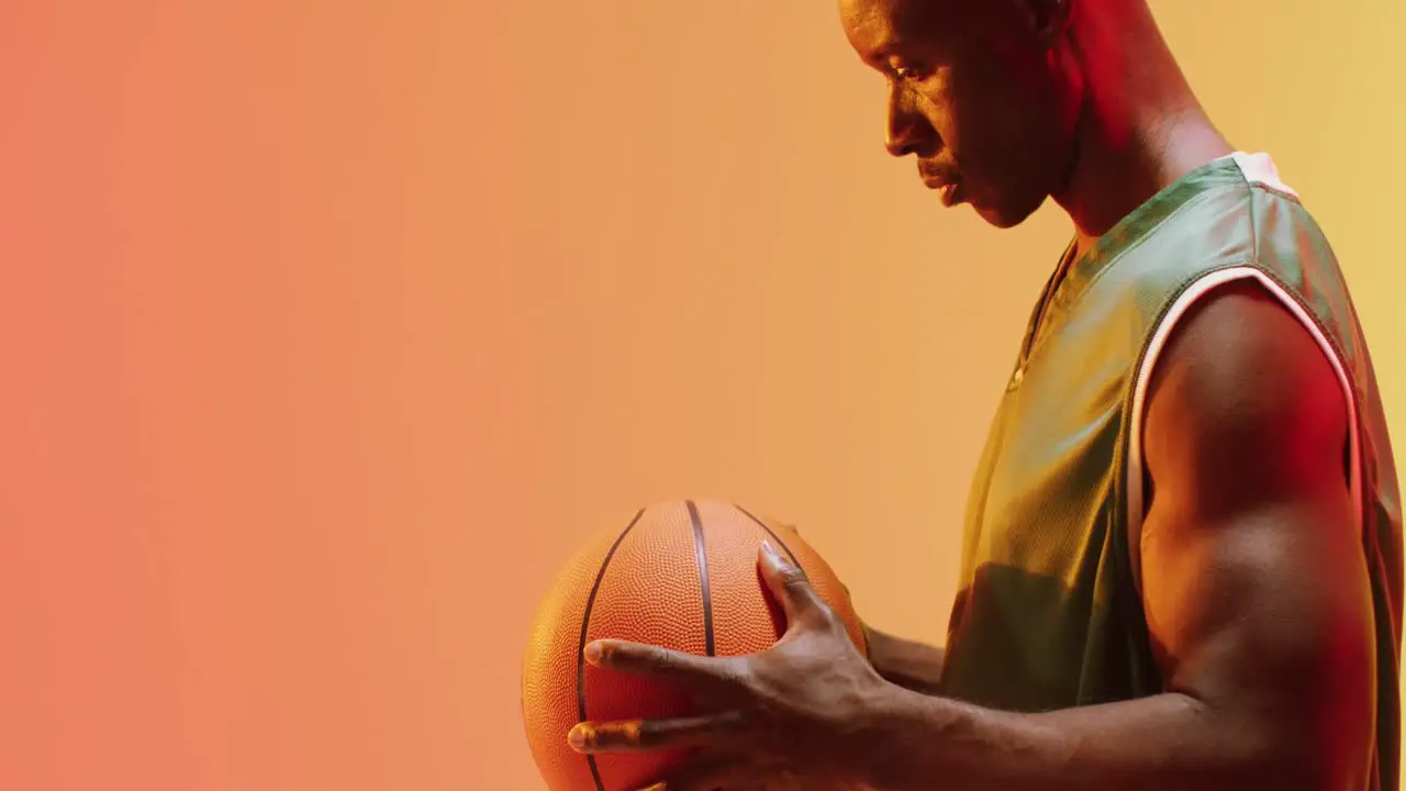 Video of african american male basketball player spinning ball on orange background