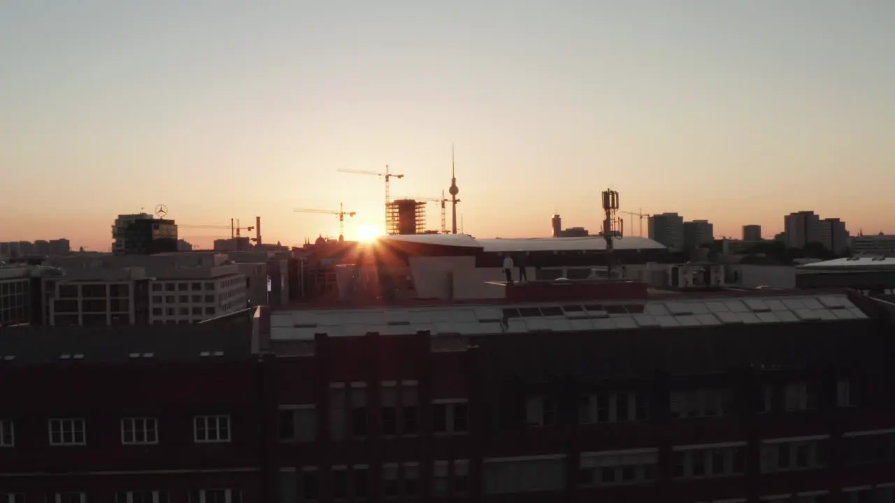 Confident Young Man Guy standing on rooftop in Golden Hour light with Urban Skyline of Berlin Germany and Beautiful Sunlight and Summer Vibe Aerial Establishing Shot