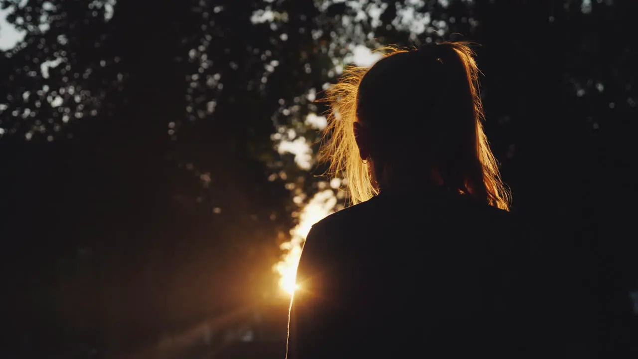 Silhouette Of A Girl Looking At The Sunset In The Park The Sun Beautifully Illuminates Her Blond Hai