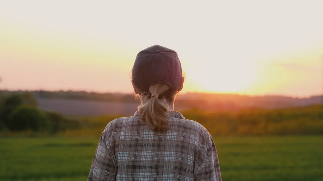 A Female Farmer Walks Through A Picturesque Field At Sunset