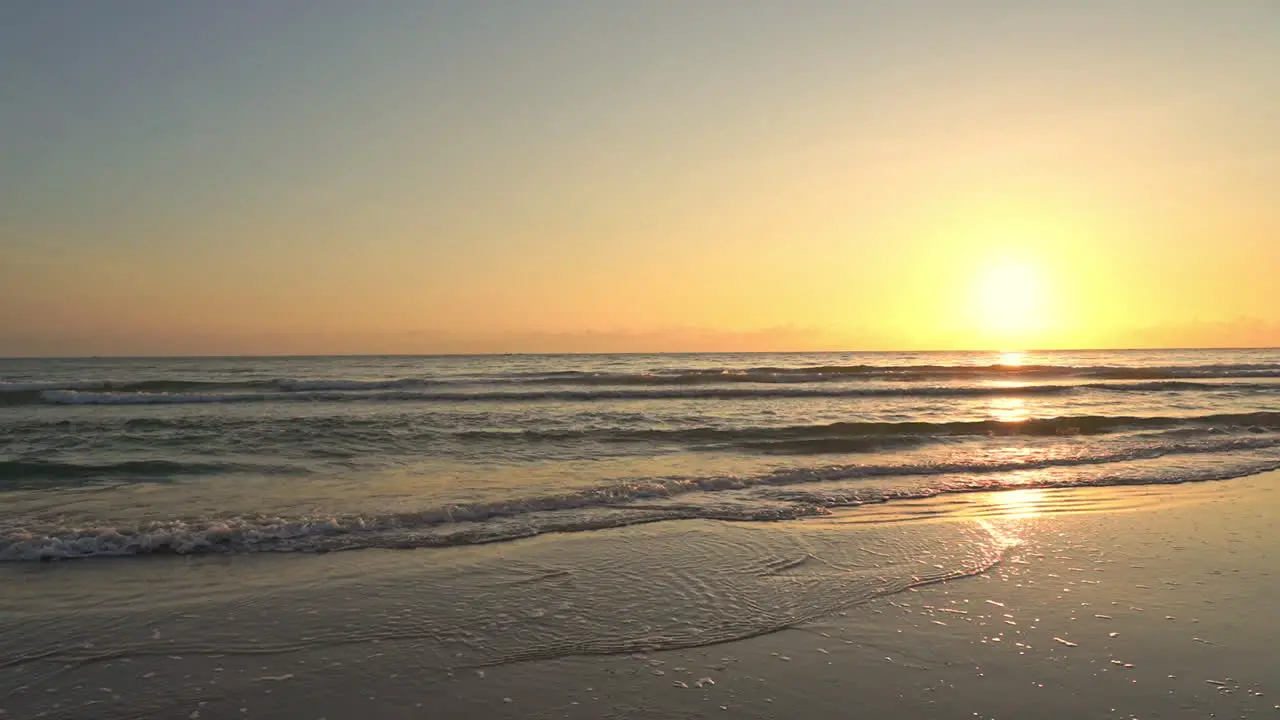 A golden idyllic sunset as the sun sets into the waters of the gentle ocean