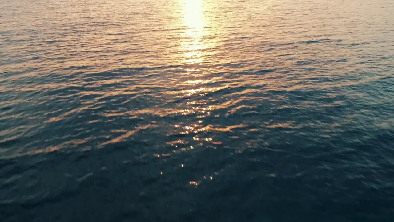 drone is flying over the sea towards the sunset