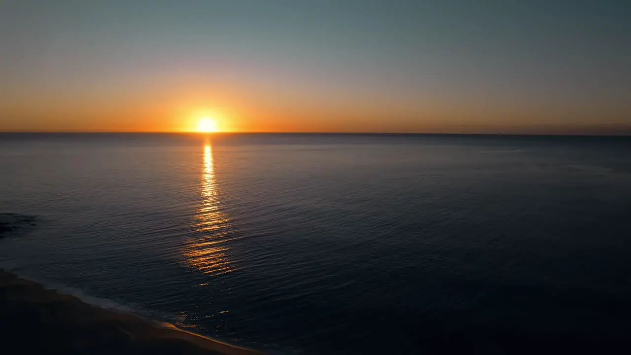 Drone Flyover Beautiful sunrise over the Pacific Ocean Sunlight reflections on water surface