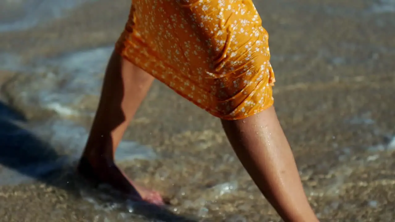 girl in a dress walks through the water on the beach