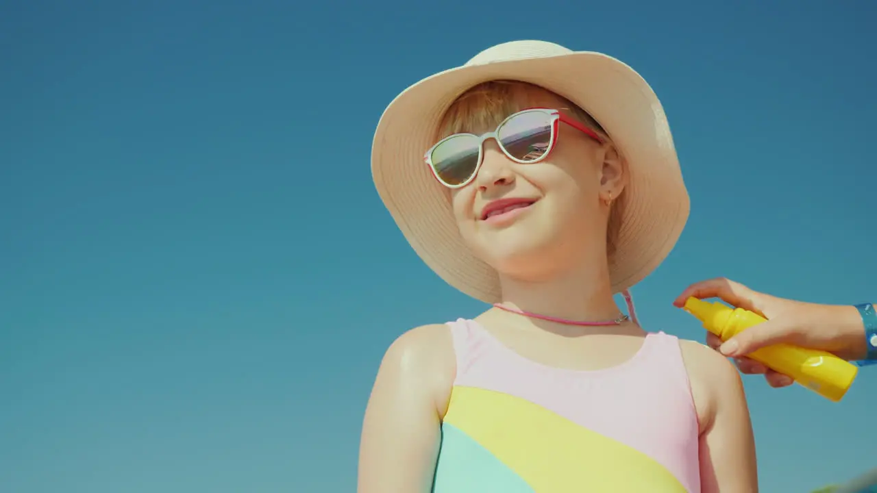 Mom Puts Sunscreen On Her Daughter's Shoulders And Neck