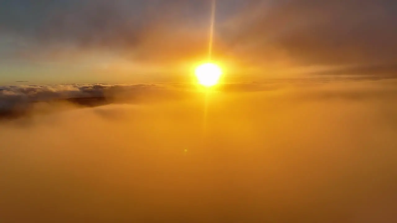 Sun glowing through the foggy cloudscape Aerial view orange setting