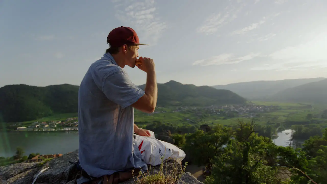 peaceful mountain ridge picknick man having a break in flowerfield stone tower enjoying the view taking in the sight landscape overview cinematic slow motion slomo male guy enjoys outdoor hills