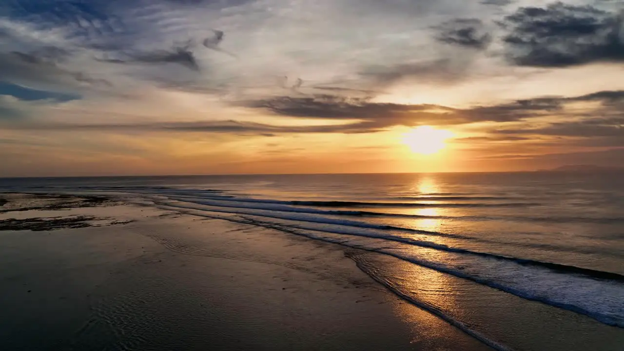 Drone clip showing bright golden sunset over ocean waves at point break in Indonesia