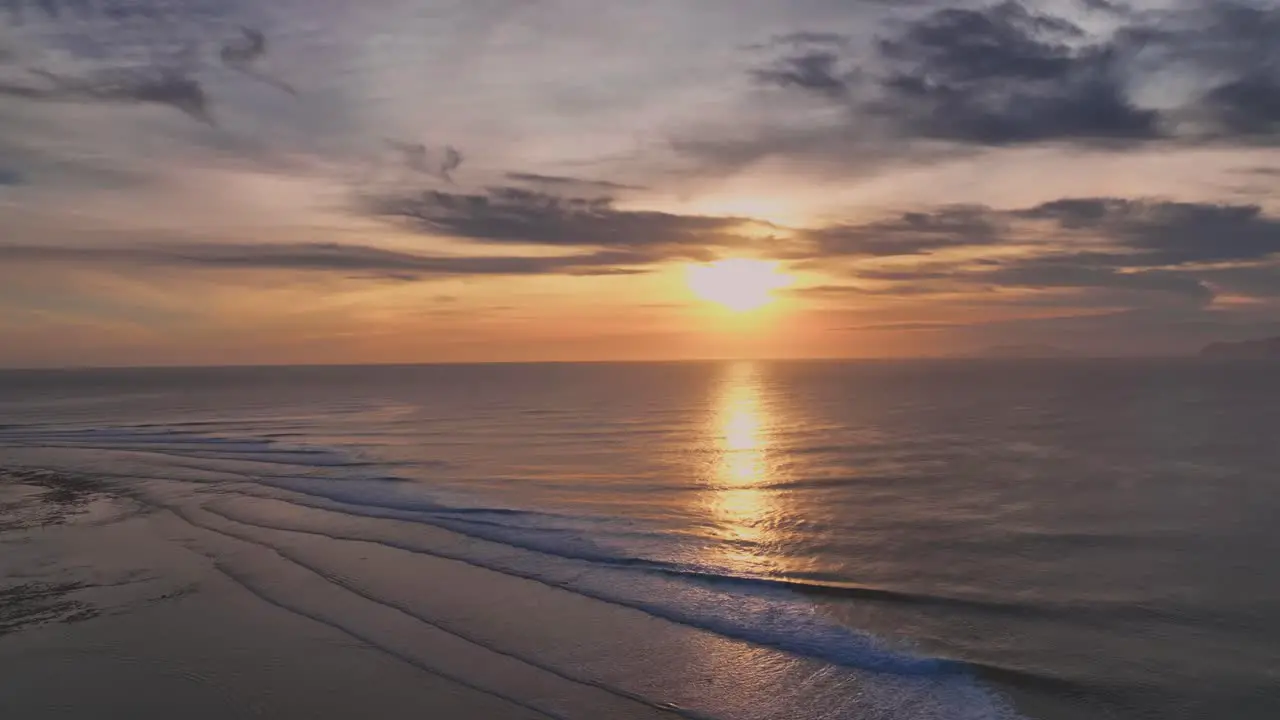 Drone clip of Golden Sunset over a coral reef surf break in the tropics with an amazing reflection bouncing off the surface of the ocean