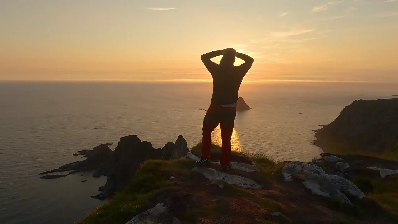 Men looking into the sunset at the ocean and island Bleiksoya rock landscape in Norway