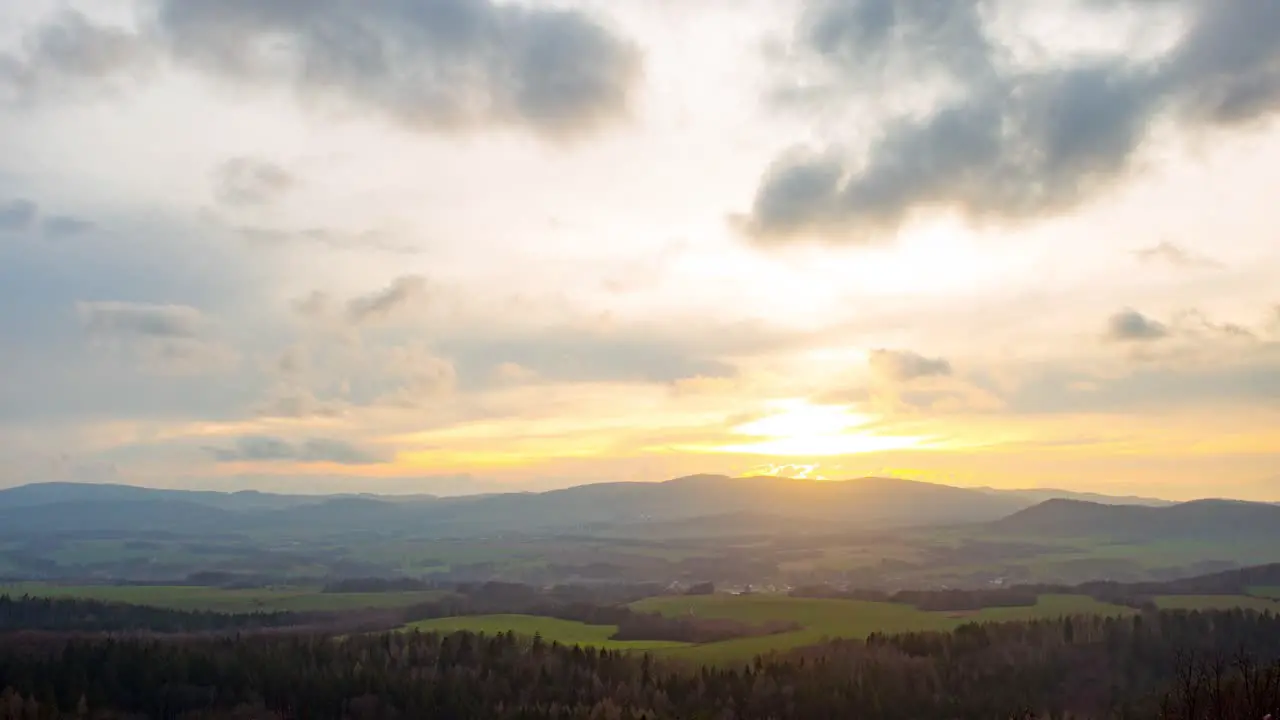 Time lapse of clouds moving fast above a mountain village during sunset