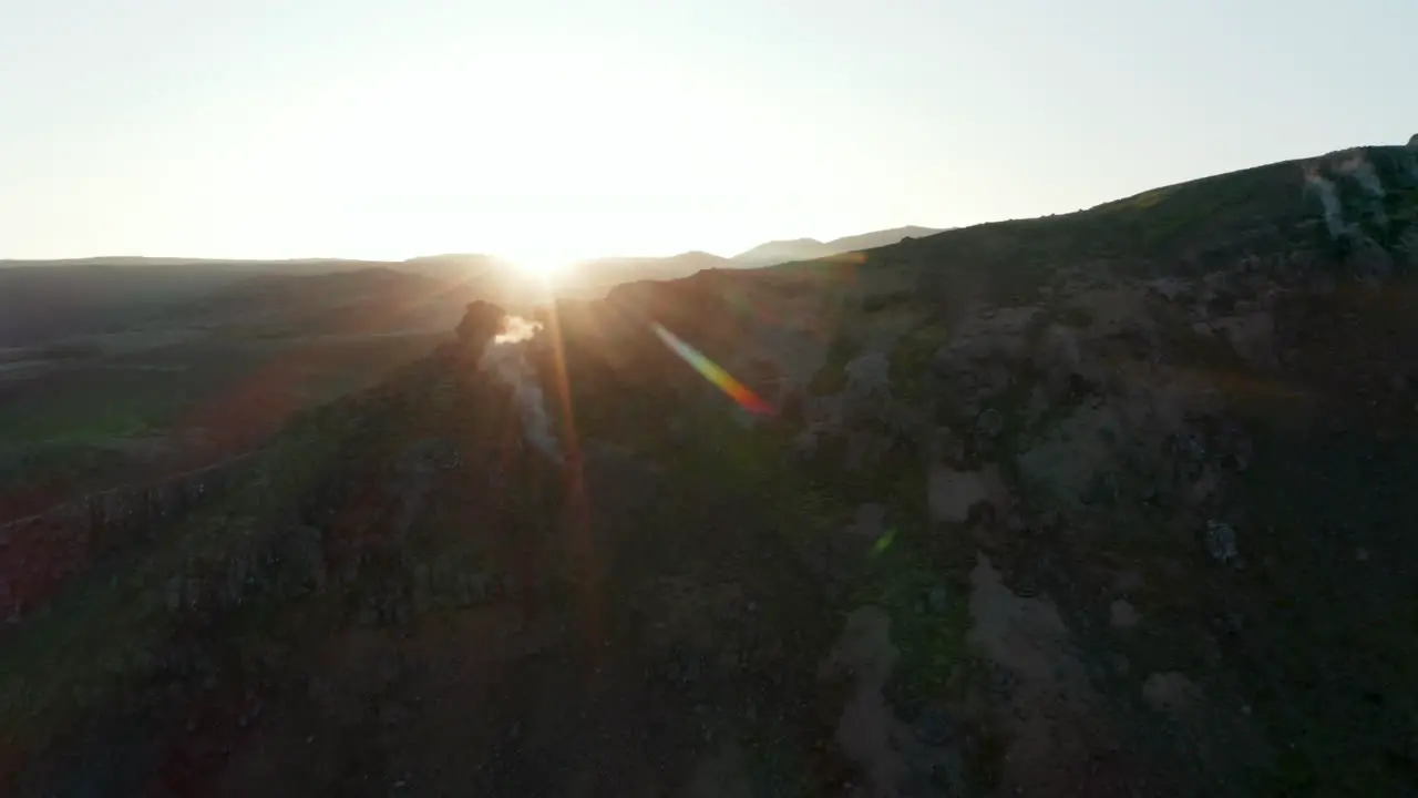 Orbit around rocky formations with hot water steaming holes in Iceland Aerial view Backlight drone view of geothermal icelandic countryside backlight at sunset