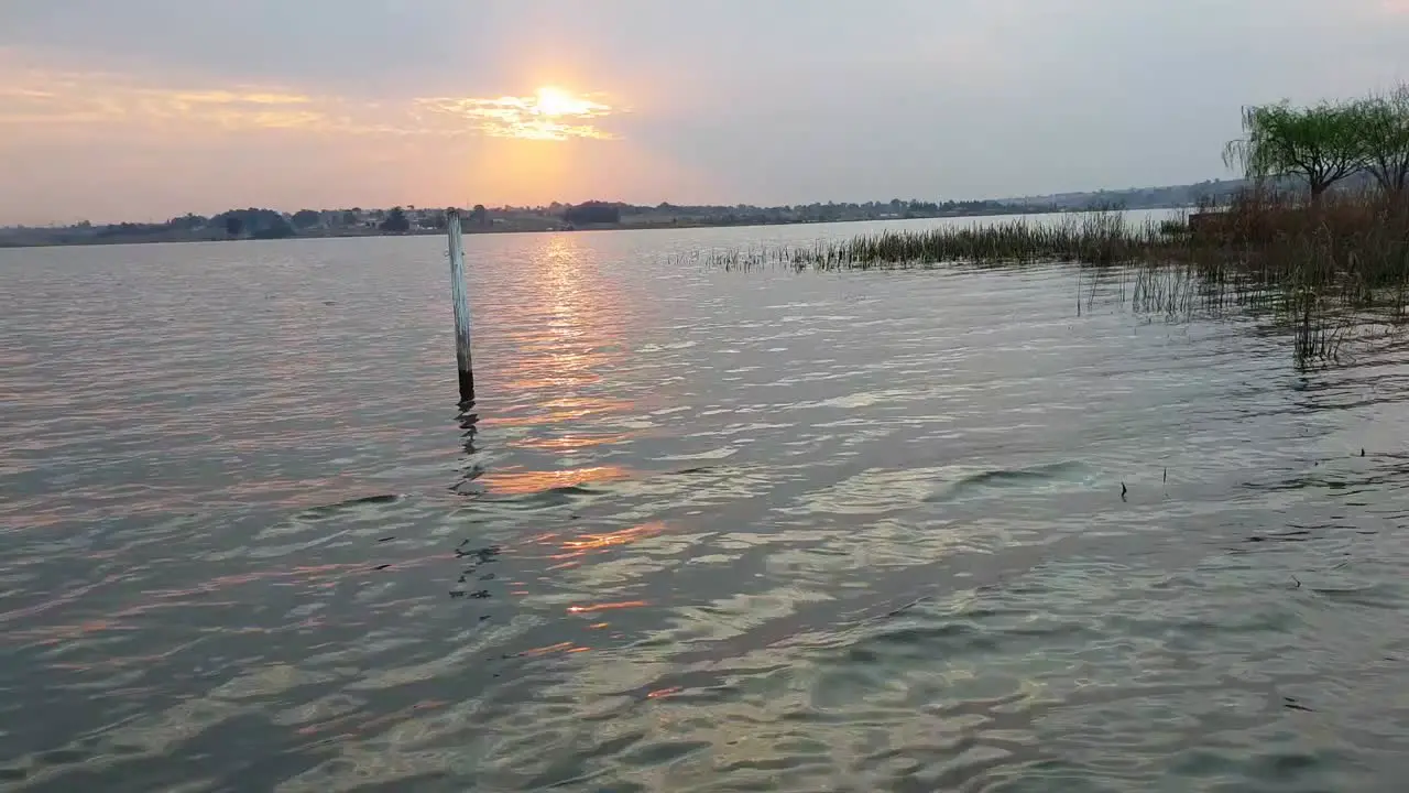 Sun setting through a few clouds on a calm lake in Africa