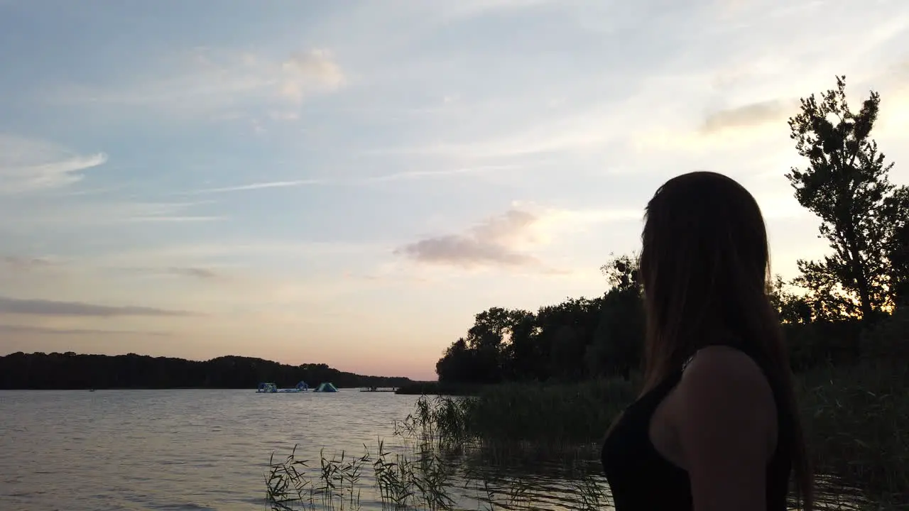 Cinematic shot of Woman on small pier admires the wonderful lake at sunset-1